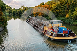 Transportation industry. Ship barge transports scrap metal and sand with gravel. Barge loaded with scrap metal is on the