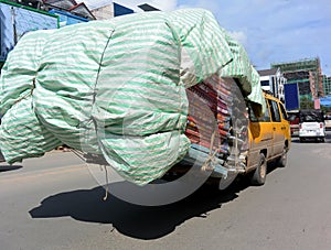 Transportation of mattresses by yellow minibus, Cambodia
