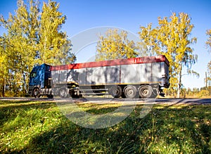 Transportation in special trailers of bulk cargoes of sand and coal on country roads. Automobile cargo transportation, industry.