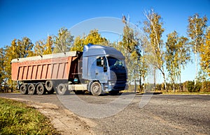 Transportation in special trailers of bulk cargoes of sand and coal on country roads. Automobile cargo transportation, industry.