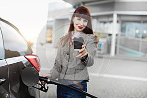 Transportation, technology, energy concept. Blurred portrait of young pretty businesslady, refueling her car at gas