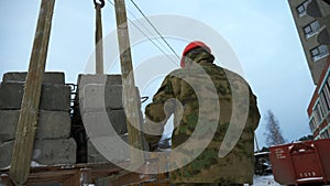 Transporting cement blocks by crane at the construction site. Clip. Builder and industrial background of a building.