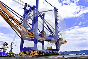 Transporting huge quay crane using self-propelled modular transporter. Moving huge quay crane from ship to harbor.