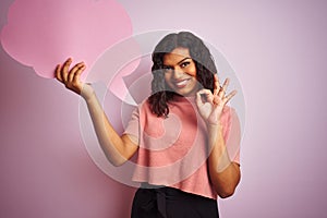 Transsexual transgender woman holding speech cloud bubble over isolated pink background doing ok sign with fingers, excellent