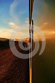 Transsiberian railway: long train making his way throught the desert in mongolia at sunset, as seen from the rear carriage.