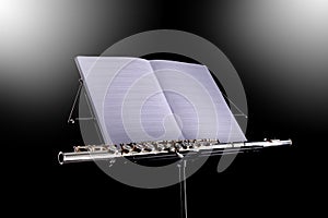 Transverse flute and blank music score rest on a black music stand isolated black background with copy space for your text