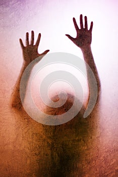 Trapped woman, back lit silhouette of hands behind matte glass