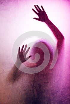 Trapped woman, back lit silhouette of hands behind matte glass