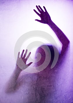 Trapped woman, back lit silhouette of hands behind matte glass