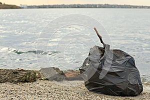 Trash bag full of garbage on beach. Space for text