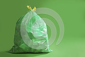 Trash bag full of garbage on green background. Space for text