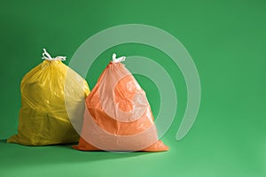 Trash bags full of garbage on green background. Space for text