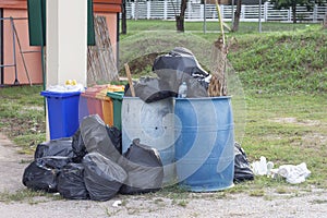 Trash bin and a black bag to hold garbage that overflows out. photo