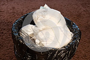 A trash bin full of dirty used baby`s diapers.  Disposable nappies