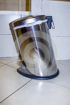 Trash can, chrome, inclined with a pedal, in the bathroom.