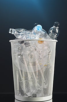 Trash can with wasted plastic bottles, black background