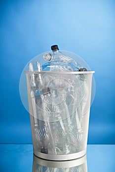 Trash can with wasted plastic bottles, blue background