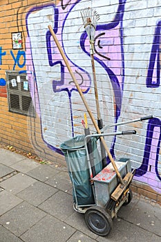 Trash cleaning cart with bin and broom standing on the street