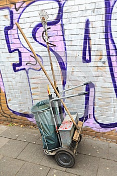 Trash cleaning cart with bin and broom standing on the street