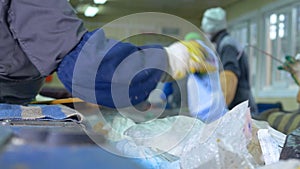 Trash conveyor. Unrecognizable laborers at conveyor sorting garbage at a recycling plant.