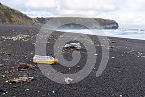 Trash in the sand, plastic waste by the ocean, sad and unsustainable photo