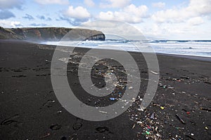 Trash in the sand, plastic waste by the ocean, sad and unsustainable photo