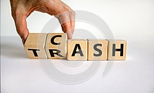 From trash to cash. Male hand flips wooden cubes and changes the word `trash` to `cash` or vice versa. Beautiful white table,