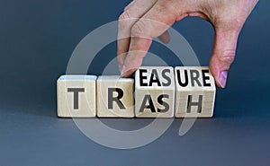Trash to treasure symbol. Businessman turns cubes and changes the word trash to treasure. Beautiful grey table, grey background.