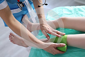 Traumatologist applies bandage to child injured leg