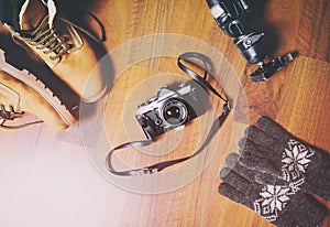 Travel accessories set on wooden background: hiking leather boots, vintage camera, tripod .