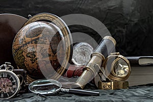 Travel or adventure concept background. Pocket watch, binoculars, antique compass, globe, magnifying glass and stack of books on