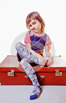 Travel and adventure concept. Beautiful little child girl sitting on suitcase against white background