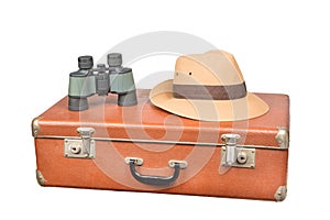 Travel and adventure concept. Vintage brown suitcase with binoculars and fedora hat isolated on white