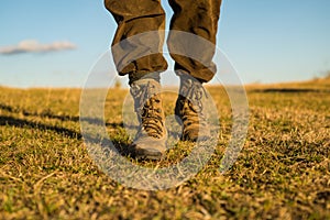 Travel adventure. future. military shoes. male feet in green boots. hynter searching for victim in grass field. going to