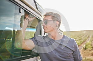 Travel, adventure and man by his car in the countryside while on a roadtrip during summer vacation. Sunshine, outdoors