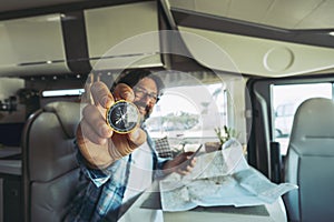 Travel and adventure people lifestyle. One man portrait showing compass and using road map paper to choose next trip destination.