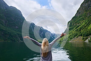 Travel adventure woman celebrates arms raised at view of majestic glacial valley fjord lake on exploration discover
