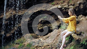 Travel adventure woman taking photos of a smartphone on a mountain waterfall, enjoying the beautiful scenery of nature