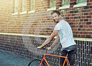 Travel, bicycle and portrait of man by brick wall in city for sightseeing on vacation or adventure. Smile, walking and