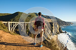 Travel in Big Sur, man Hiker with backpack enjoying view Bixby Bridge, California, USA