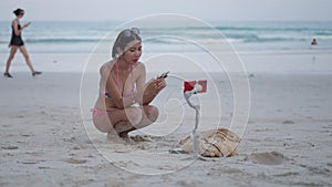 Travel blogger live stream from the tropical beach. Asian girl using mobile phone to check comment while online