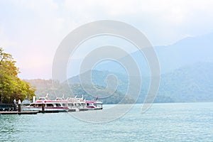 Travel boats parking at  the pier with sunset and mountain scenery background, sun moon lake, Taiwan