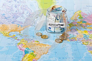 Travel budget concept. Money saved for vacation in glass jar on map