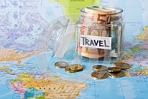 Travel budget concept. Money saved for vacation in glass jar on map