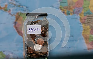 Travel budget concept. Money saved for vacation in glass jar on world map background, copy space. coins for big