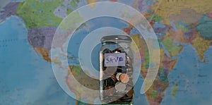 Travel budget concept. Money saved for vacation in glass jar on world map background, copy space. coins for big