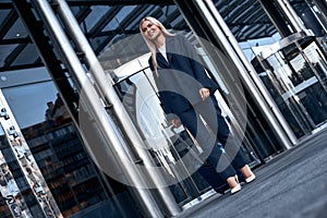 Travel, business trip. Woman in a suit walking out of airport