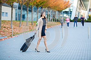 Travel. Business Woman in airport talking on the smartphone while walking with hand luggage in airport going to gate