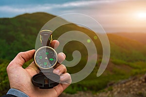 Travel, camping, orienteering and navigation concept - black magnetic compass close-up in a man s hand, blurred landscape