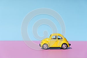 Travel car concept background. Yellow toy car on empty minimal pastel background. Driving, riding, road idea